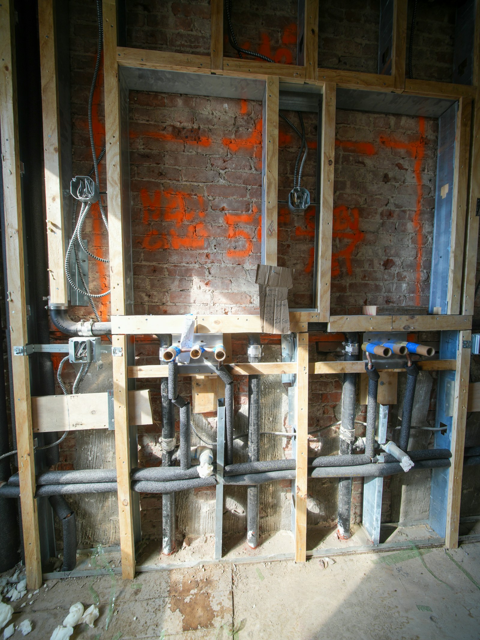 Exposed plumbing and electrical services in a wall during building fit-out.