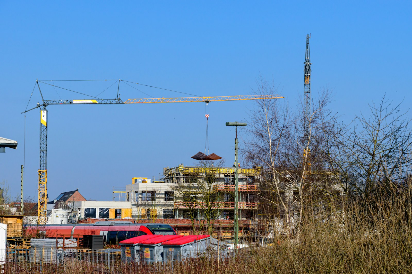 Tower cranes above a building with scaffolding during construction.