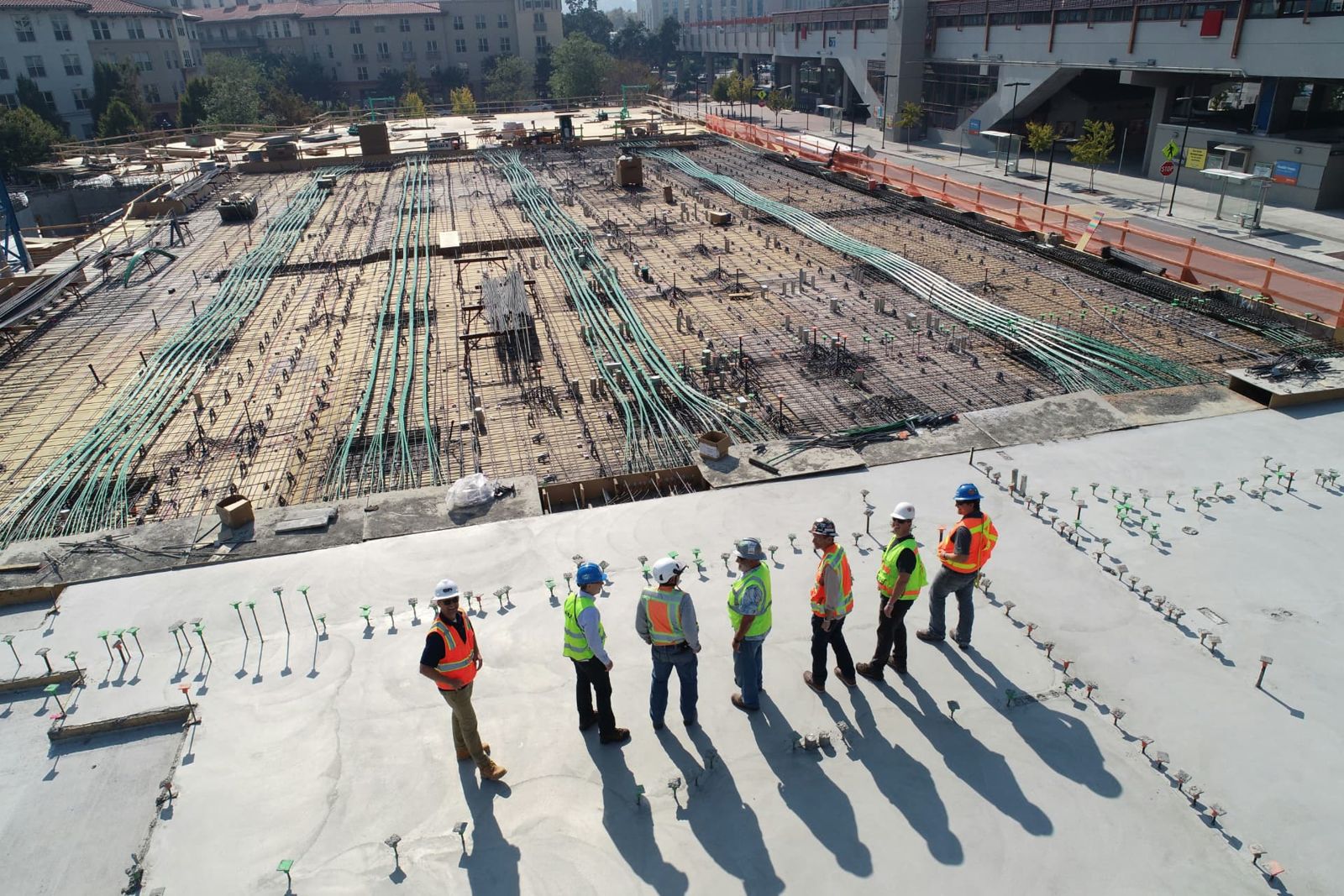 A crew in high-visibility vests walking a concrete deck.