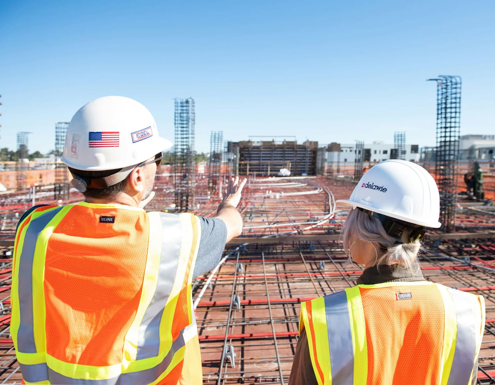 Two site leads in hard hats reviewing a deck under construction.