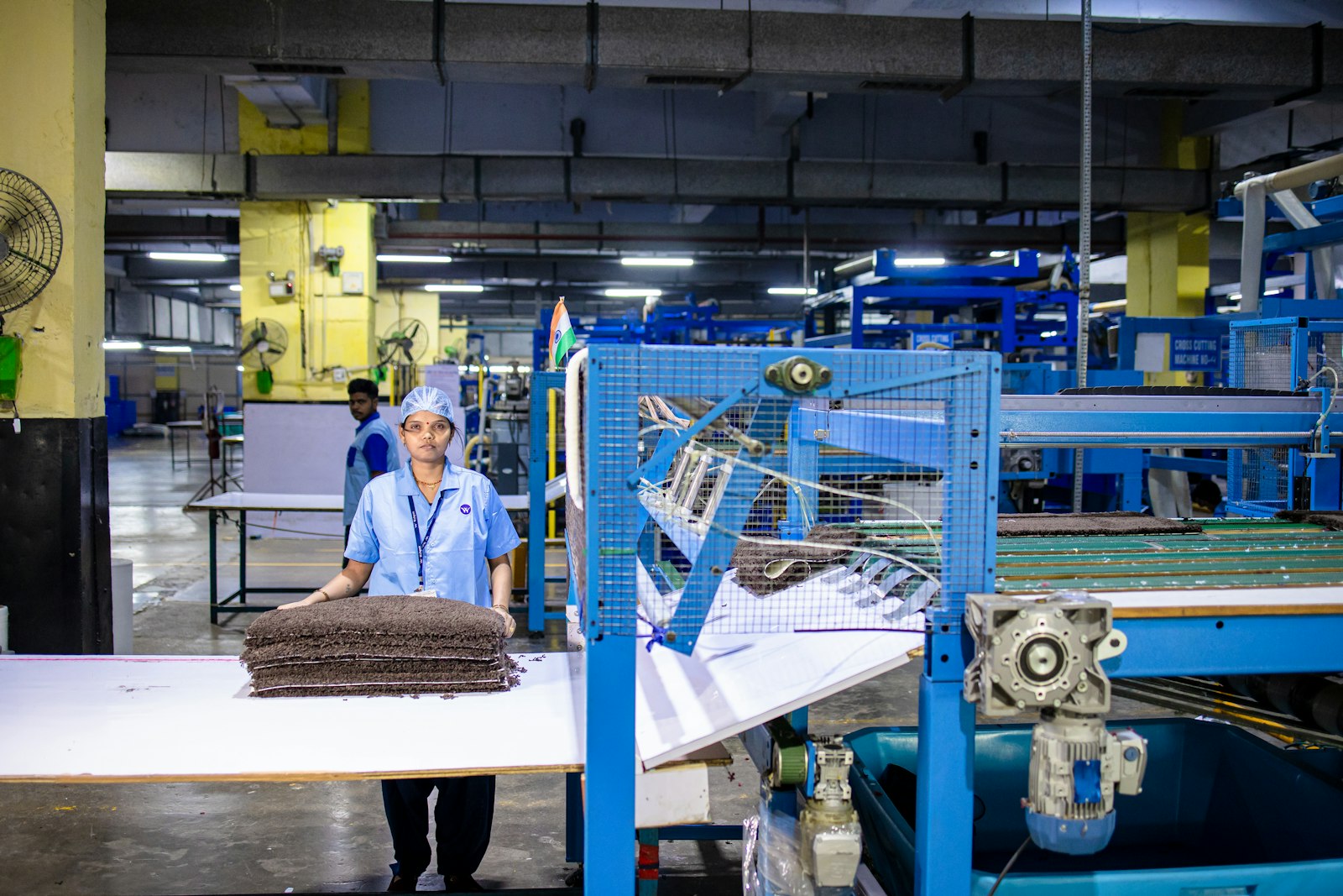 A production worker in a hairnet and uniform standing at a factory line.