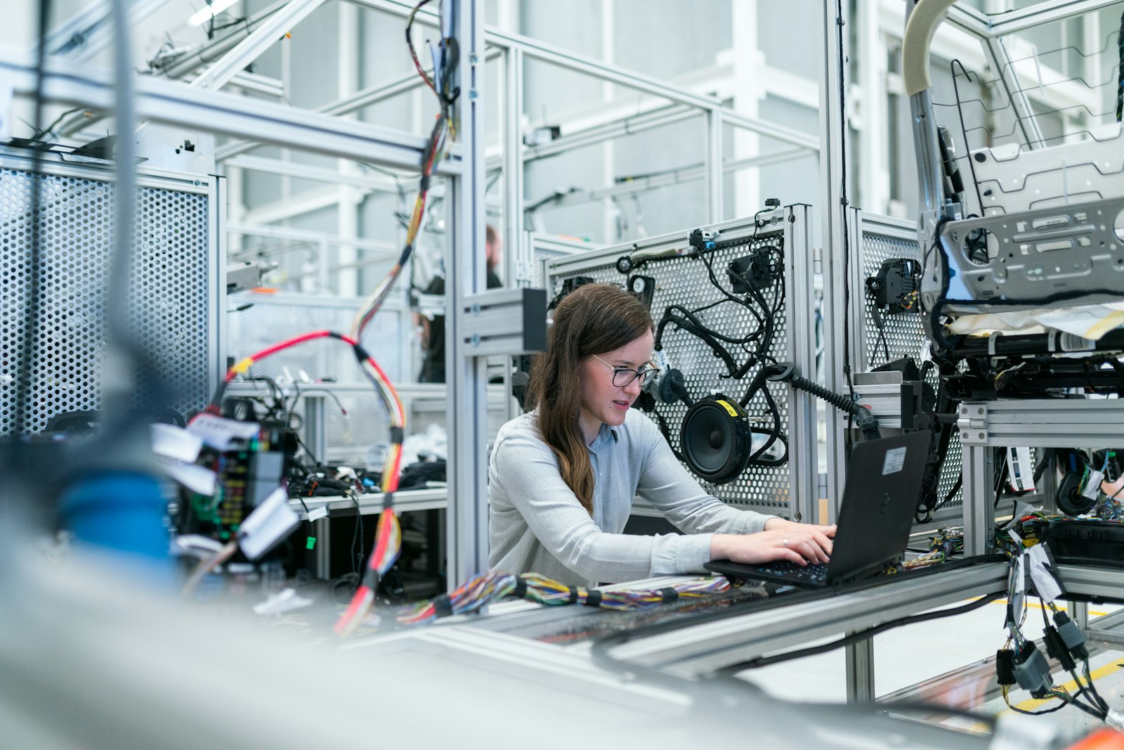 An engineer working at a laptop beside automated production equipment.