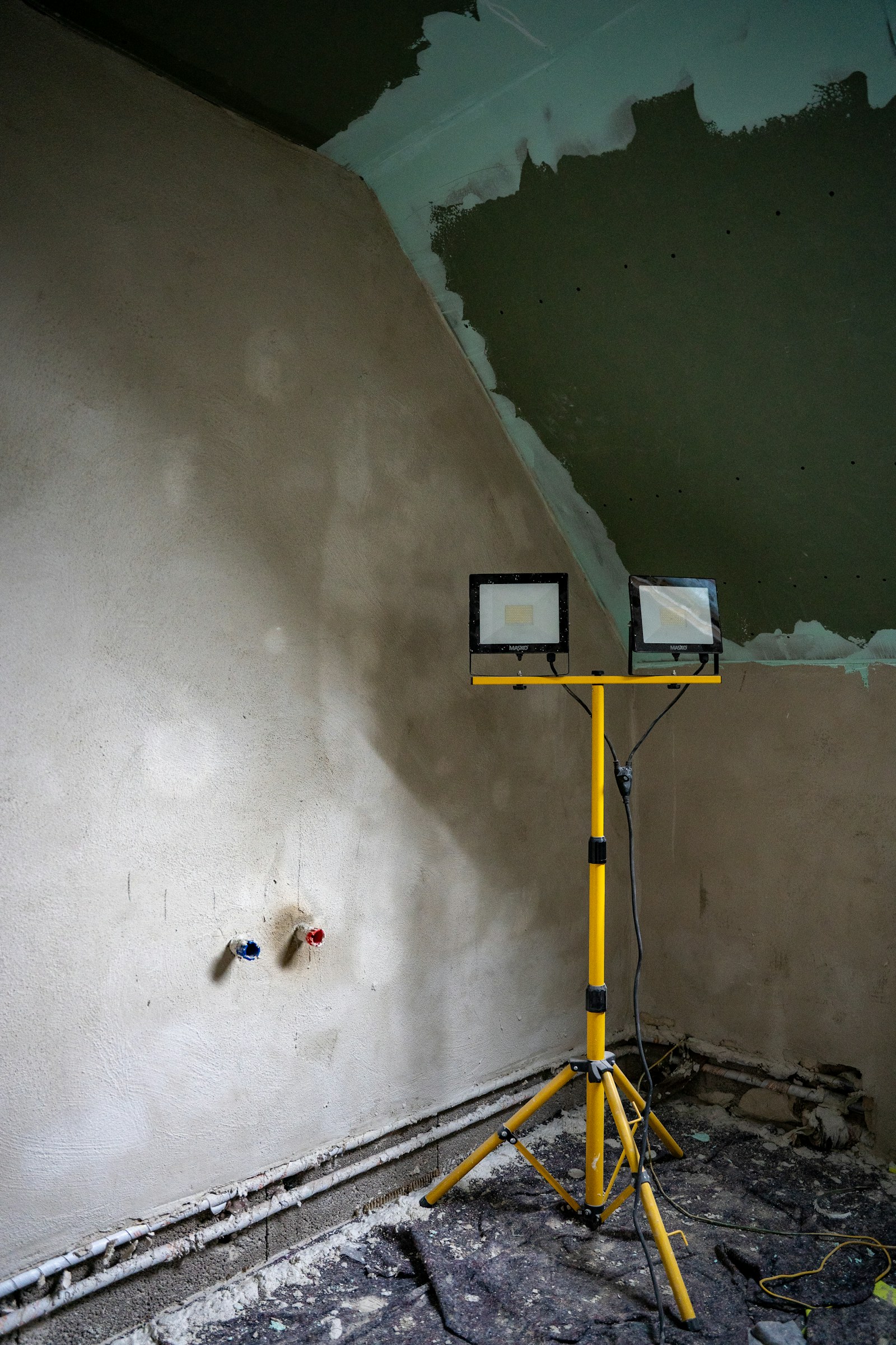 Temporary task lighting beside freshly plastered walls during interior construction.